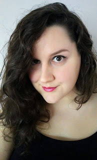 A dark haired woman in a black shirt smiling at the camera.